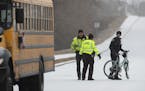 A Brooklyn Park Police officer carries a bicycle away from the scene where a bicyclist was killed after colliding with a school bus Wednesday morning 