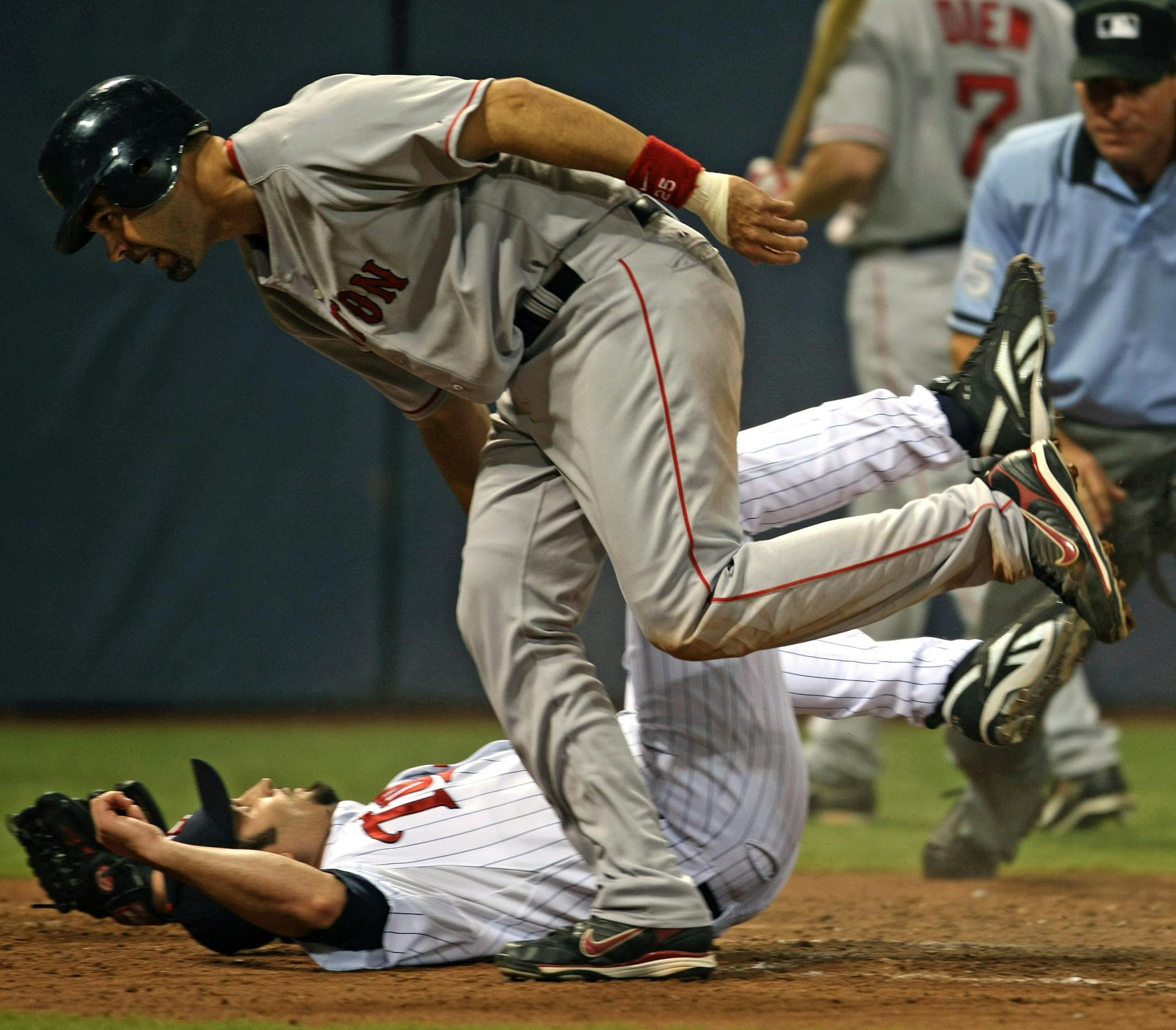 Minnesota Twins vs. Boston Red Sox. (left to right) Twins pitcher Juan Rincon was run over by Boston's Mike Lowell as he scored the go-ahead run in the 5th inning on a wild pitch by Rincon. Rincon was covering home as Twins catcher Joe Mauer went after the ball.