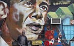 A man walks away after leaning his bicycle against a mural of President Barack Obama, created by the Kenyan graffiti artist Bankslave, at the GoDown A