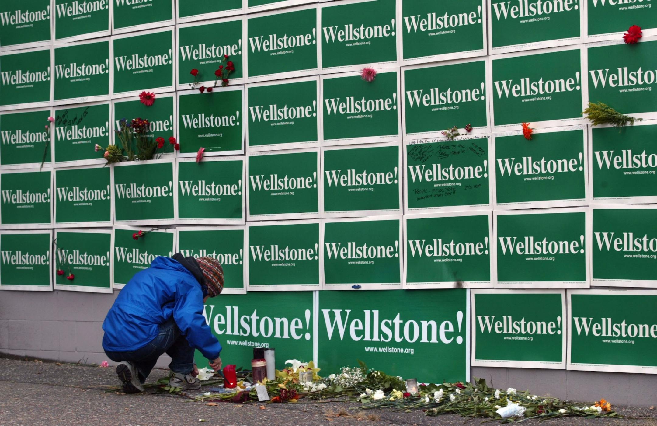 Wellstone campaign worker Kate Ryan Reiling of St. Paul lights candles under a wall filled with campaign signs outside the late senator's St. Paul campaign headquarters, the site of a makeshift memorial to Wellstone.