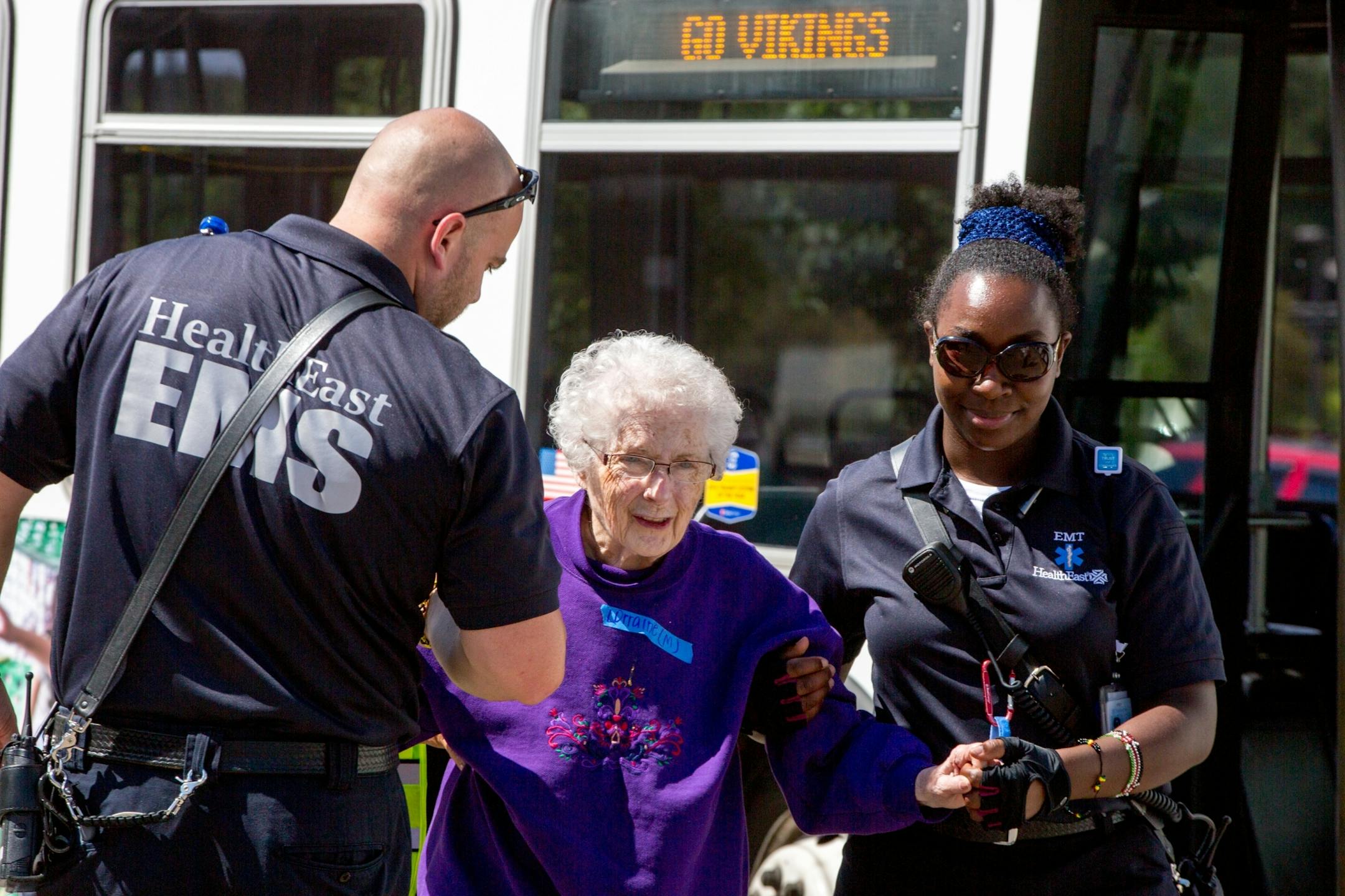 EMS helps a woman off of the bus and back to White Pine Senior Living in Mendota Heights after they were evacuated following an alleged armed robbery on July 29, 2017.