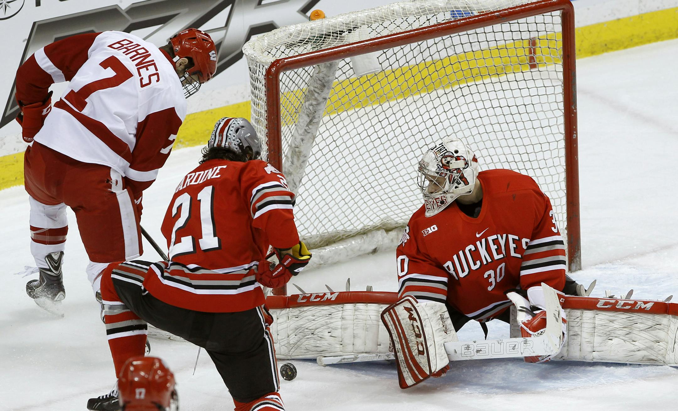 Ohio State goalie Christian Frey (30) deflects a shot by Wisconsin forward Tyler Barnes (7) in front of Ohio State defenseman Sam Jardine (21) during the first period of the championship college hockey game of the Big 10 Conference tournament in St. Paul, Minn., Saturday, March 22, 2014. (AP Photo/Ann Heisenfelt)