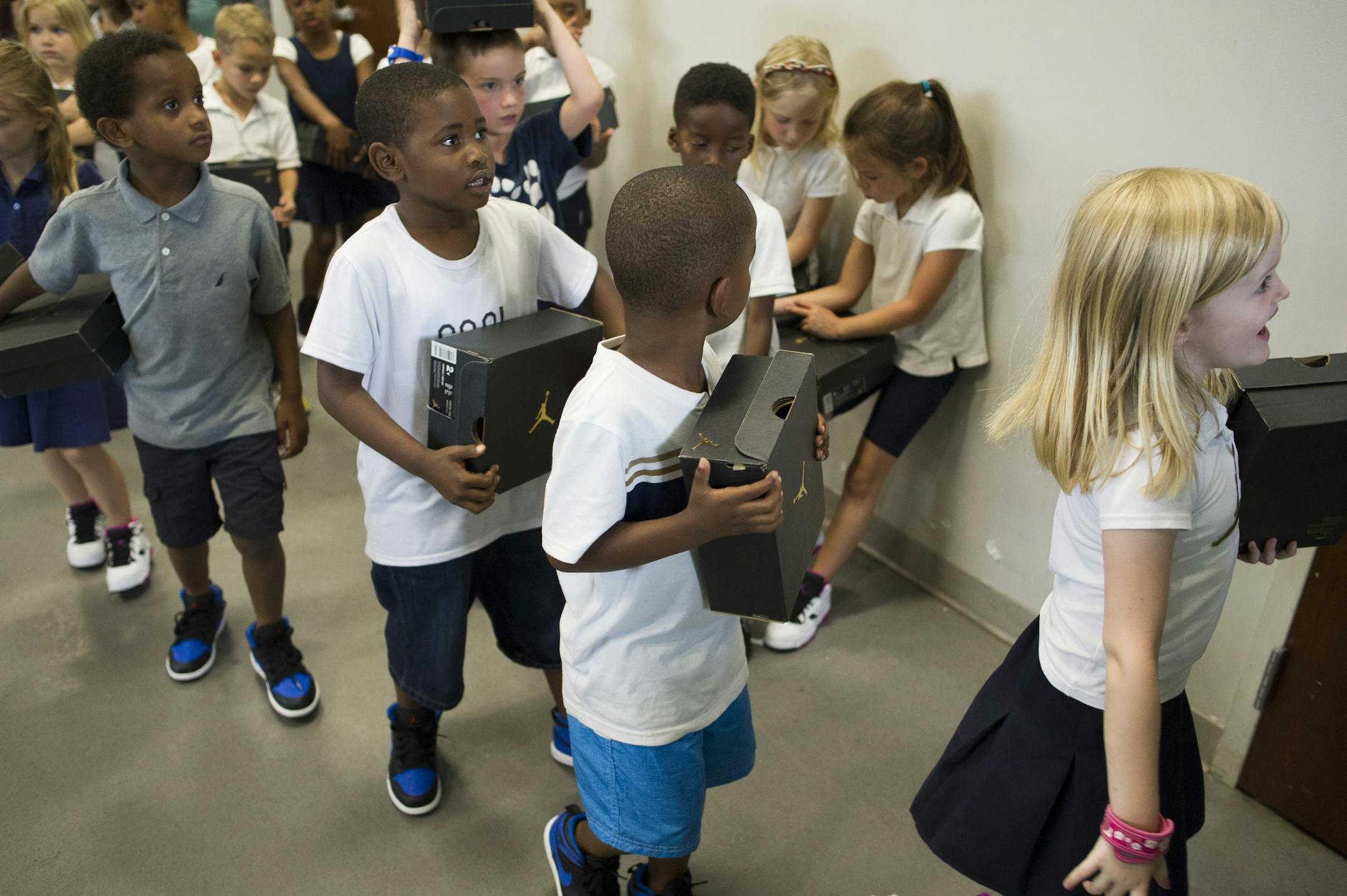 Students wear their new Nike Jordan shoes while carrying a box containing their old shoes after having their feet washed and shoes put on by the WNBA Champion Minnesota Lynx at Payne Elementary School in Washington, Wednesday, June 6, 2018. Payne Elementary has the highest homeless student population in D.C..