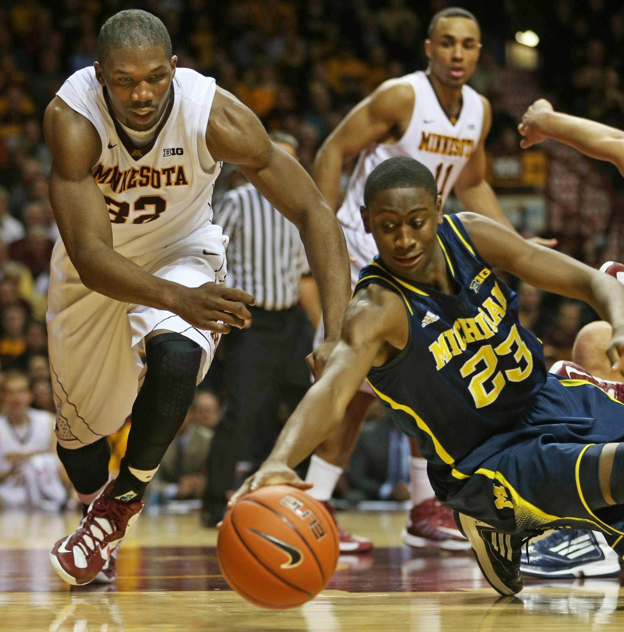 At Williams Arena on the U of M campus in a game between the Gophers and the Michigan Wolverines, Trevor Mbakwe(32) dives for a loose ball against Caris LeVert(23) of Michigan .