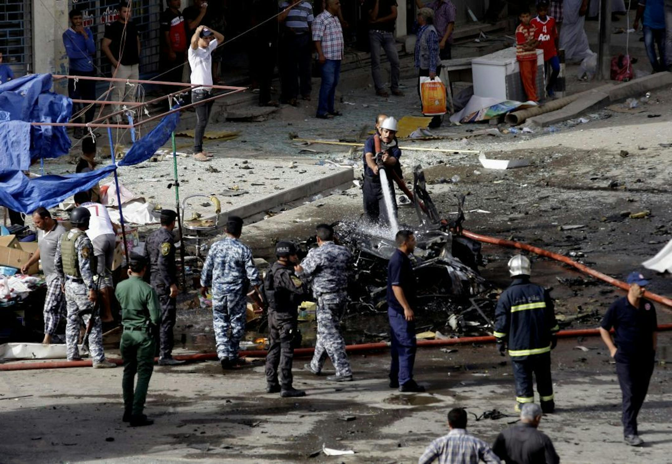 Security forces inspect the scene of a car bomb attack in the Baghdad, Iraq, Monday, May 27, 2013. A parked car bomb explosion in the busy commercial Sadoun Street in central Baghdad, killed and wounded scores of people, police said.