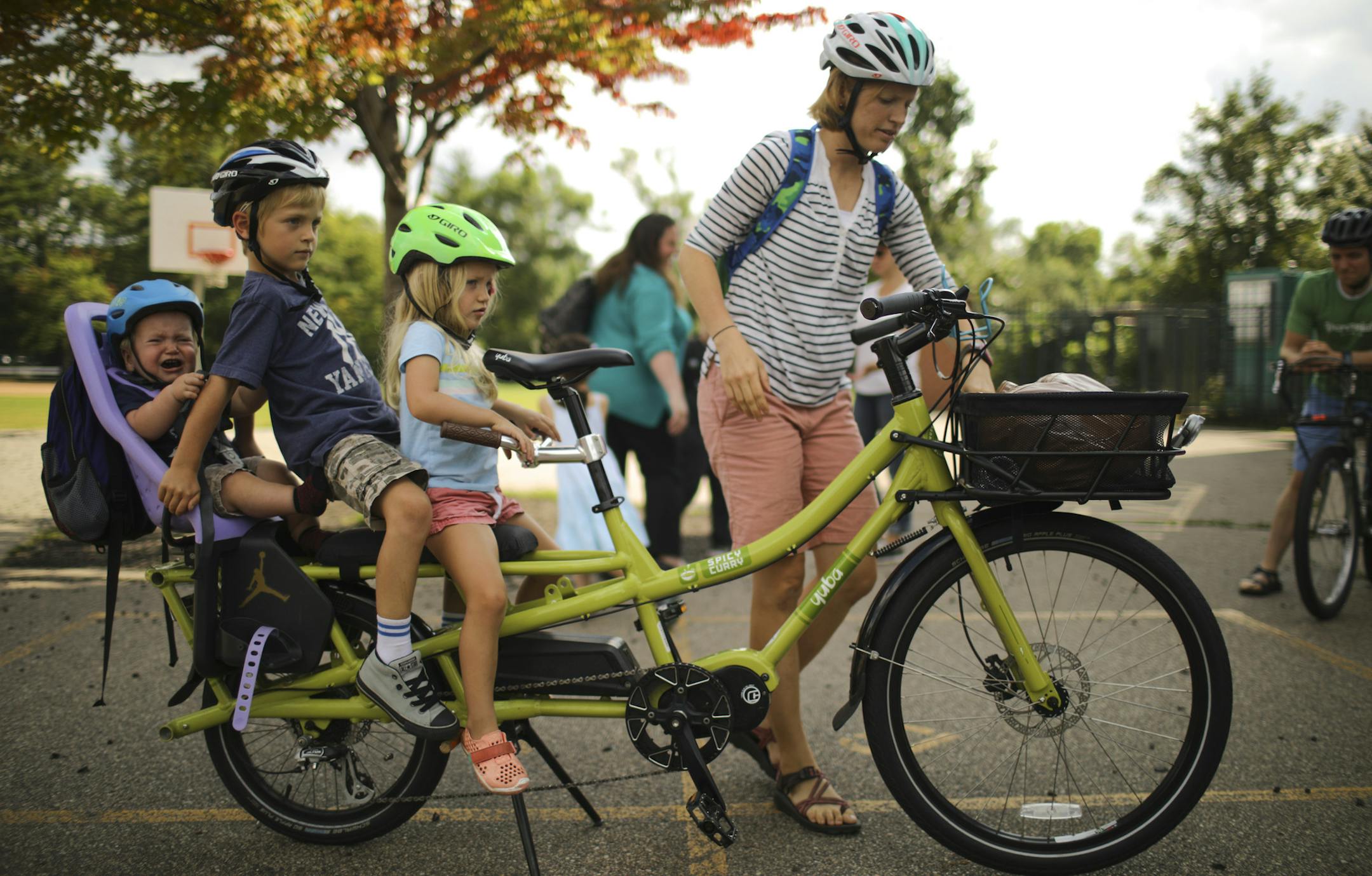 Stephanie Brodegard reached for a water bottle after getting her three kids situated on her cargo bike after picking up her son. Grant, 6, from school.