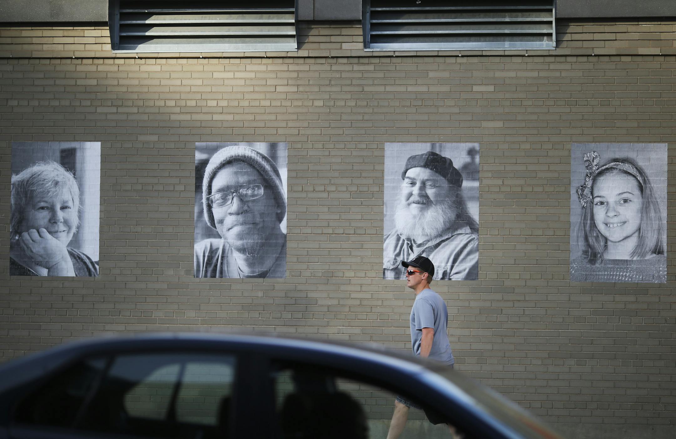 A man walked past portrait photographs that are displayed outside St. Paul's CHS Field in Lowertown as part of the Inside Out project in St. Paul, Minn. on Thursday, May 28, 2015. ] RENEE JONES SCHNEIDER • reneejones@startribune.com The big, black-and-white head shorts are part of an international participatory art project founded by a French artist who goes by the moniker JR. Nearly 200,000 people from more than 100 countries and territories have collaborated on projects designed to "tur