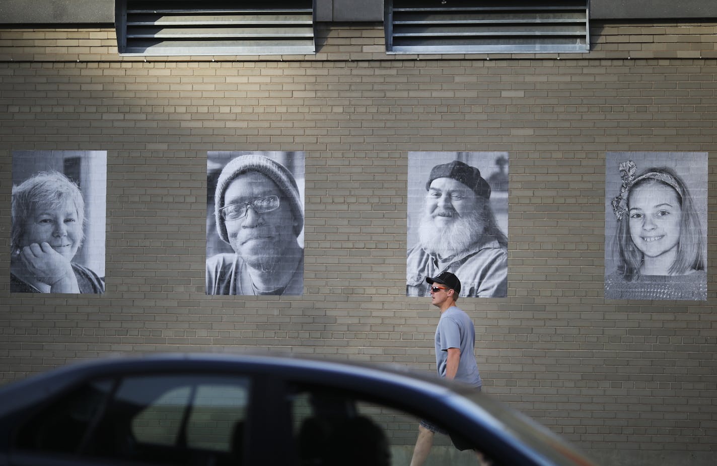 A man walked past portrait photographs that are displayed outside St. Paul's CHS Field in Lowertown as part of the Inside Out project in St. Paul, Minn. on Thursday, May 28, 2015. ] RENEE JONES SCHNEIDER &#x2022; reneejones@startribune.com The big, black-and-white head shorts are part of an international participatory art project founded by a French artist who goes by the moniker JR. Nearly 200,000 people from more than 100 countries and territories have collaborated on projects designed to "tur