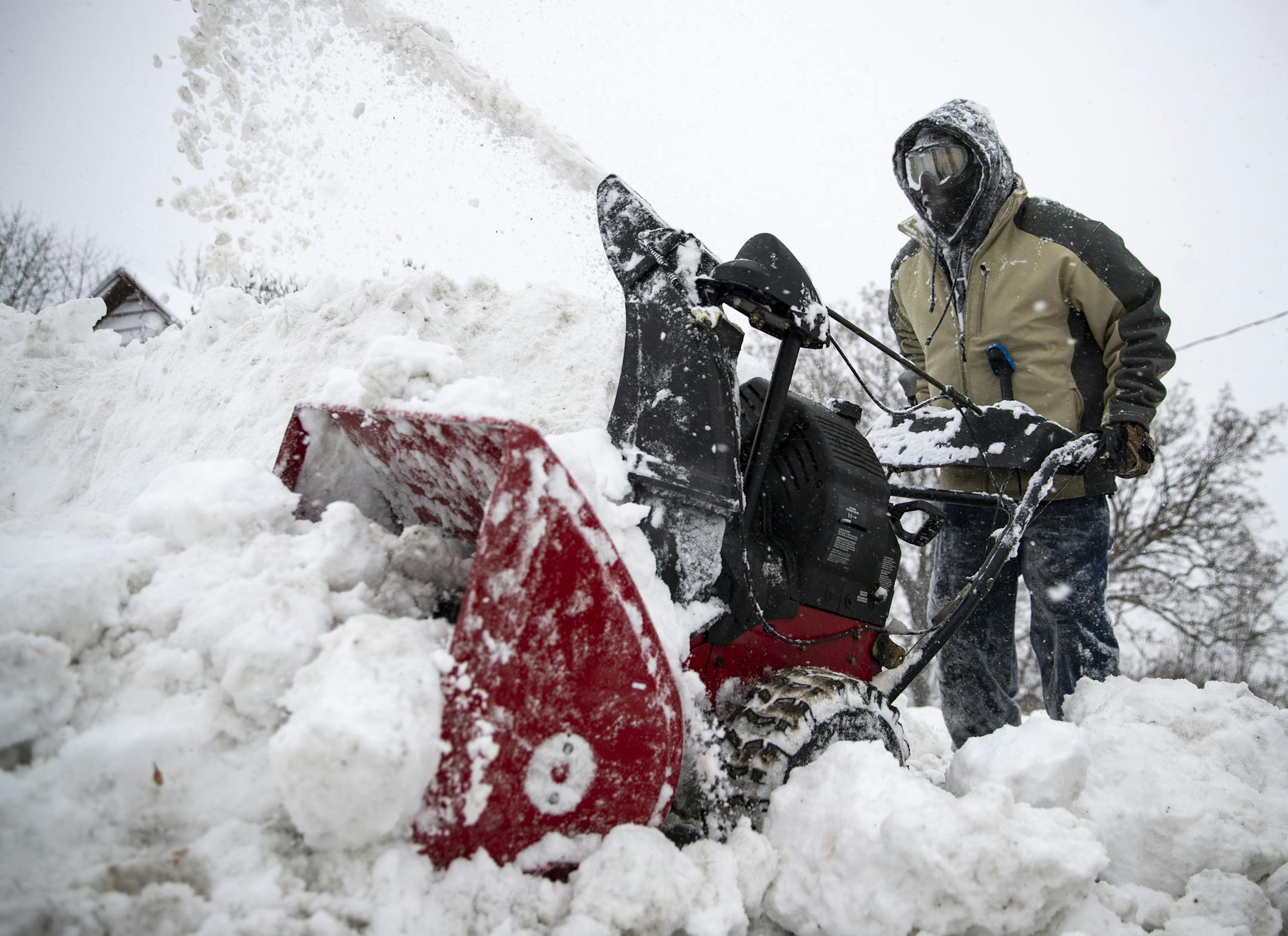 Mike Taylor works to blow a large pile of snow pushed in front of his driveway by plows throughout the night, Sunday, Dec. 1, 2019, in Duluth, Minn. (Alex Kormann/Star Tribune via AP)