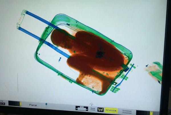 In this photo released by the Spanish Guardia Civil on Friday, May 8, 2015, a boy curled up inside a suitcase is seen on the display of a scanner at t