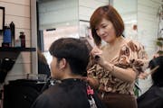 Kim Huynh, owner of Mai Hoa Beauty Salon, trims the hair of Peter Nguyen, 28. About four months ago, Nguyen got his first “soft perm,” which subtl
