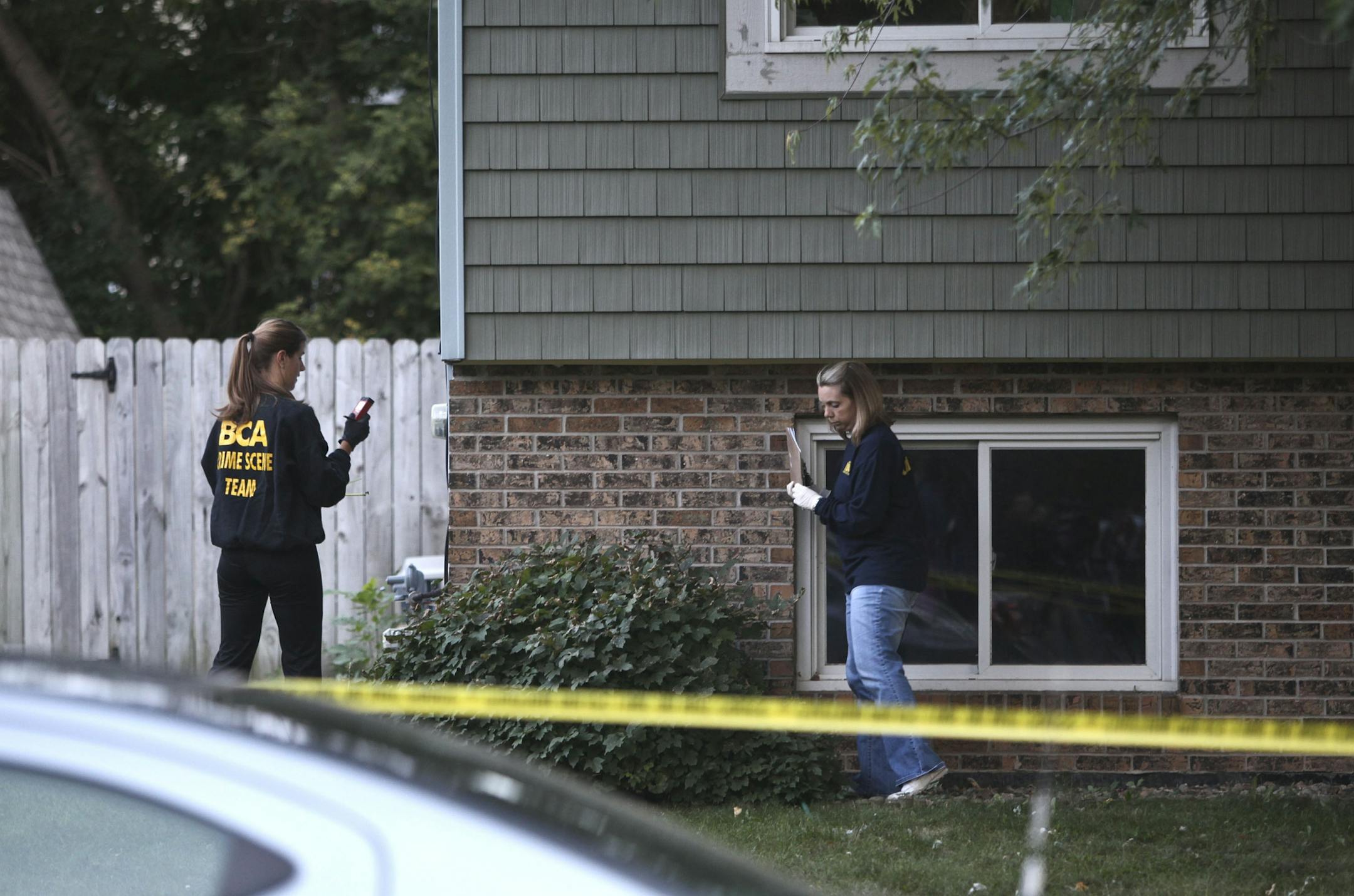 Members of the Bureau of Criminal Apprehension gather information at the house where three people were found dead in Oakdale Minn., Thursday, September 15, 2011.