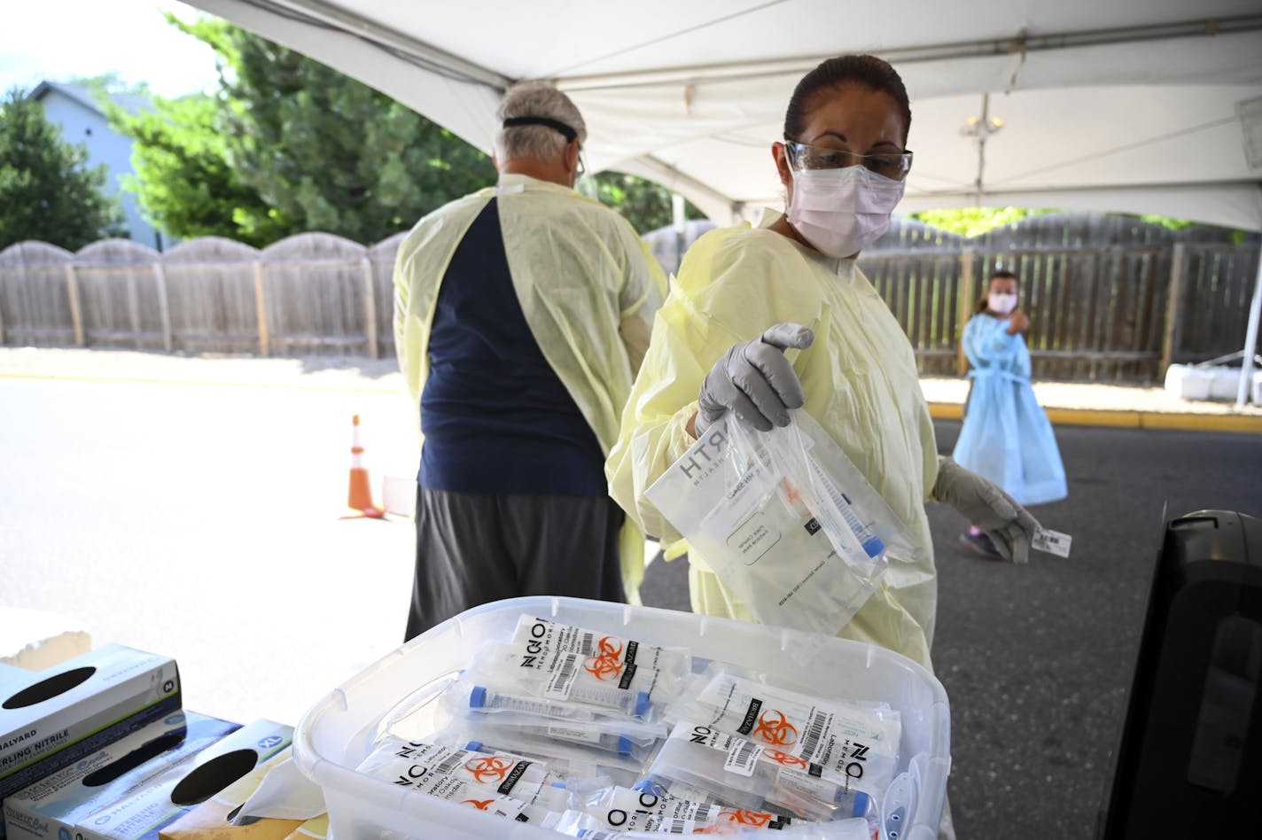 A North Memorial healthcare worker grabbed a fresh COVID-19 test kit as a patient drove up at the testing facility behind the North Memorial Health Specialty Center in Robbinsdale. ] aaron.lavinsky@startribune.com Healthcare workers tested drive-up and walk-up patients for COVID-19 behind the North Memorial Health Specialty Center on Wednesday, July 29, 2020 in Robbinsdale, Minn.