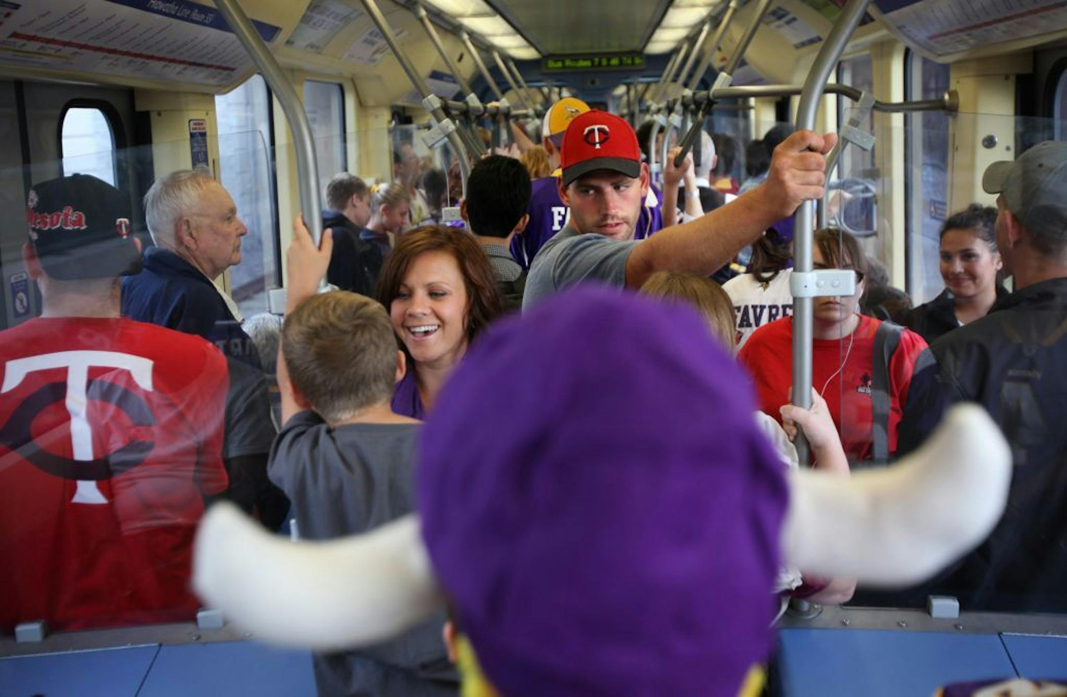 Twins fan Jon Engel (in red cap) held on tight as the lightrail packed with Twins and Vikings fans, including eight-year-old Alex Woolsey wearing Vikings horns, on the way to downtown Minneapolis