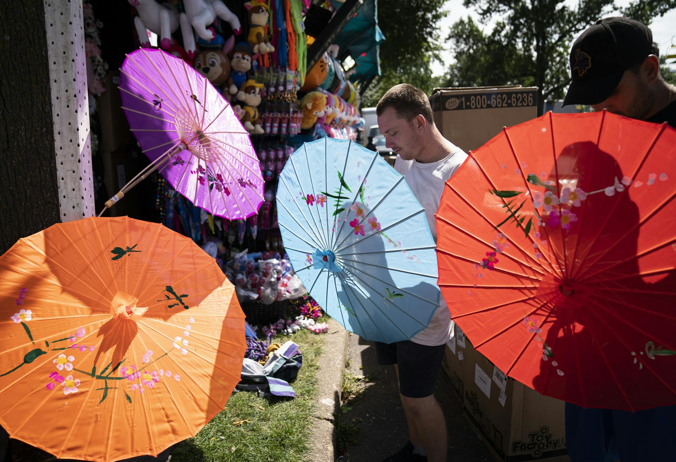 Brenden Lee and Vick Ramirez set up umbrellas for a toy and stuffed animal stand called We Dazzled on Wednesday, the day before the Minnesota State Fair opened.
