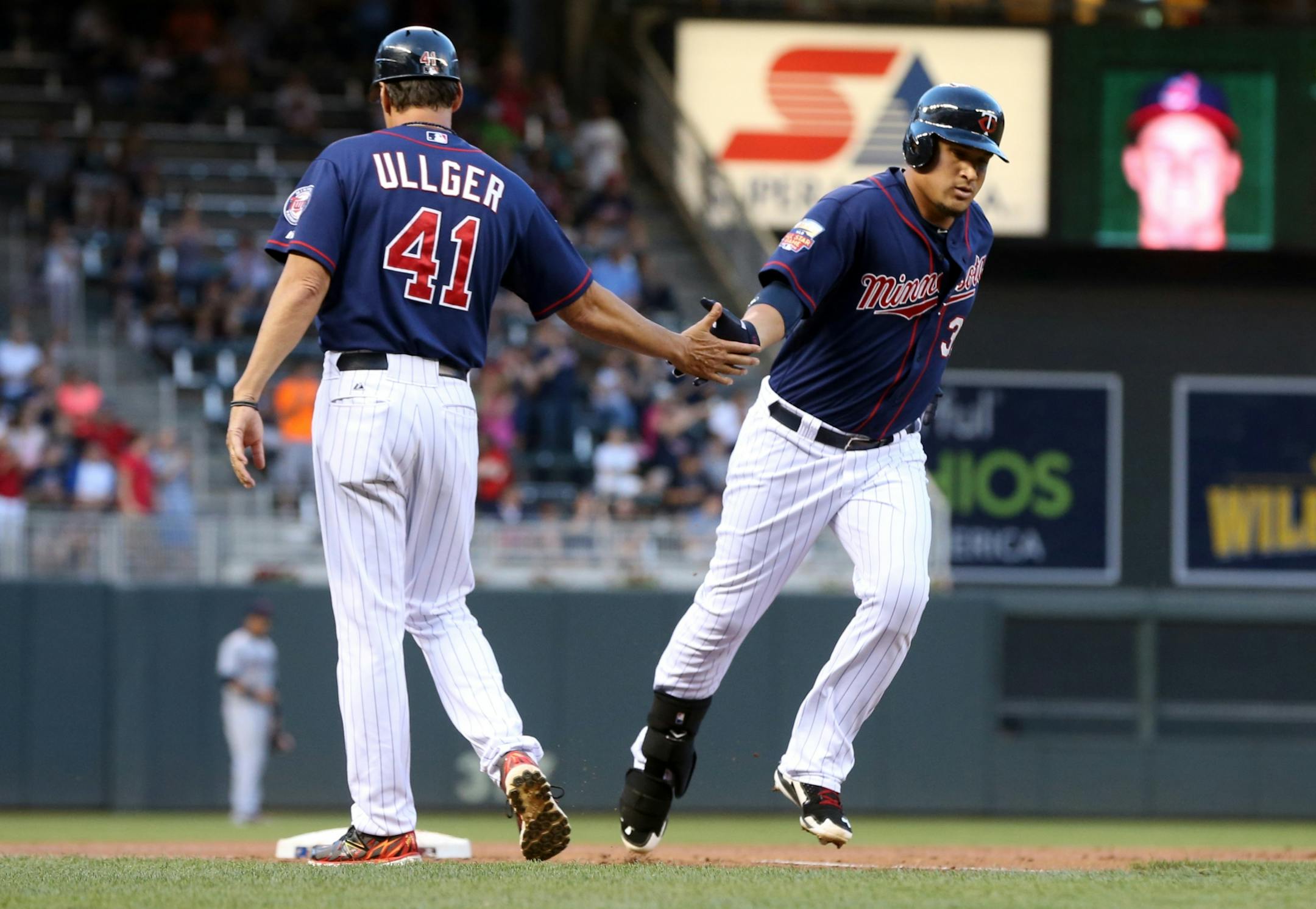 Minnesota Twins' Oswaldo Arcia, right, gets a handshake from third base coach Scott Ullger after his three-run home run off Cleveland Indians pitcher Trevor Bauer in the first inning of a baseball game,Tuesday, Aug. 19, 2014, in Minneapolis.