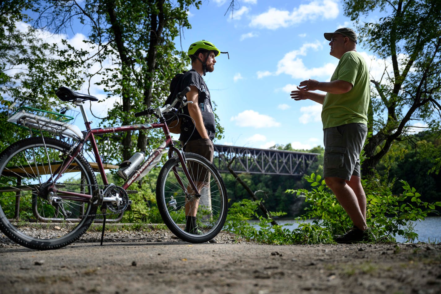 Soren Jensen, executive director of the Midtown Greenway Coalition, right, discussed the possible expansion of the Greenway to St. Paul with Noah Kleinschmidt, of Minneapolis. Behind them, the Canadian Pacific rail bridge spanning the Mississippi River that they hope will one day extend the Greenway across the river.