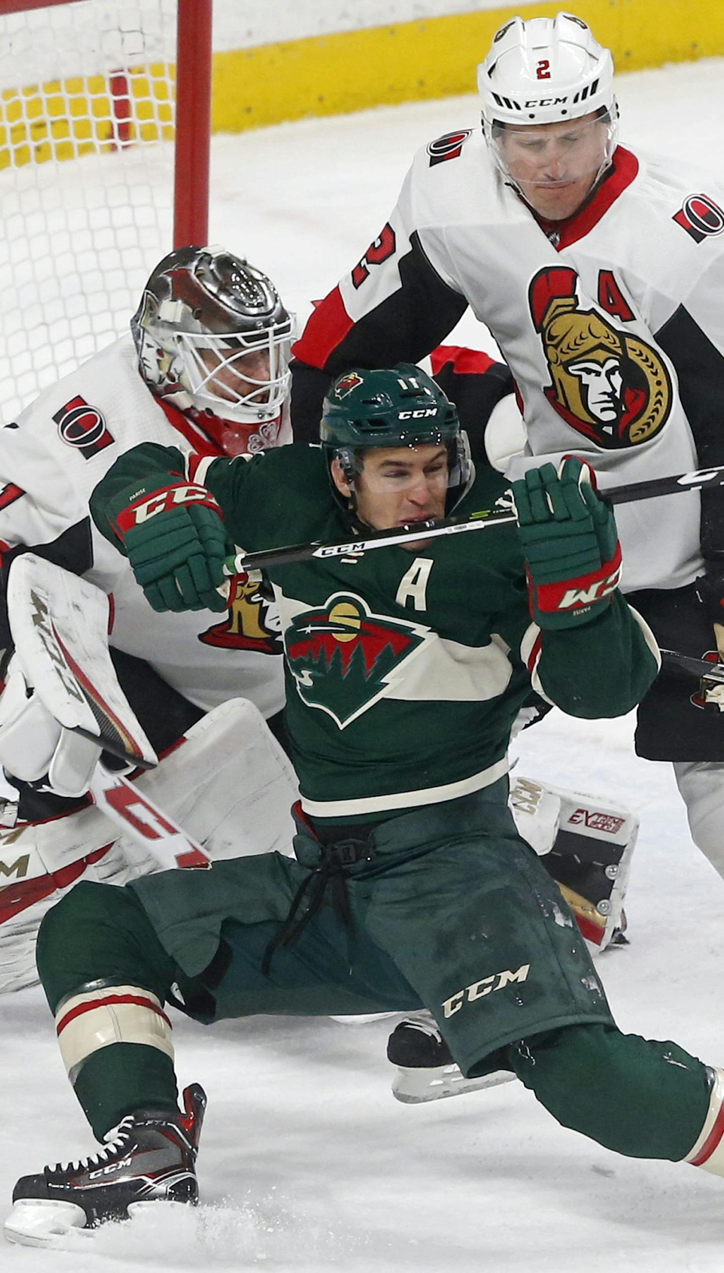 Minnesota Wild's Zach Parise, center, falls between Ottawa Senators goaltender Mike Condon, left, and Dion Phaneuf, right, as he positions himself in the first period of an NHL hockey game Monday, Jan. 22, 2018, in St. Paul, Minn. (AP Photo/Jim Mone)