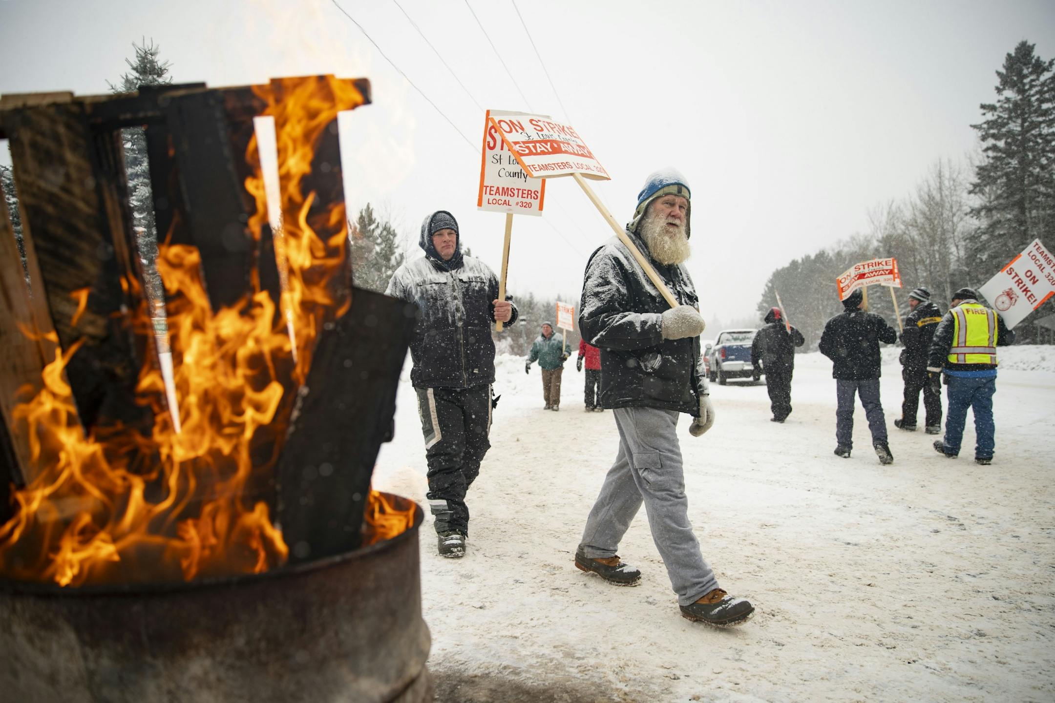 Dan Wallgren marched with snow plow drivers as they picketed in front of the St. Louis County Public Works Department building in Northern Duluth, MN as snow fell and a small fire burned on January 15, 2020.