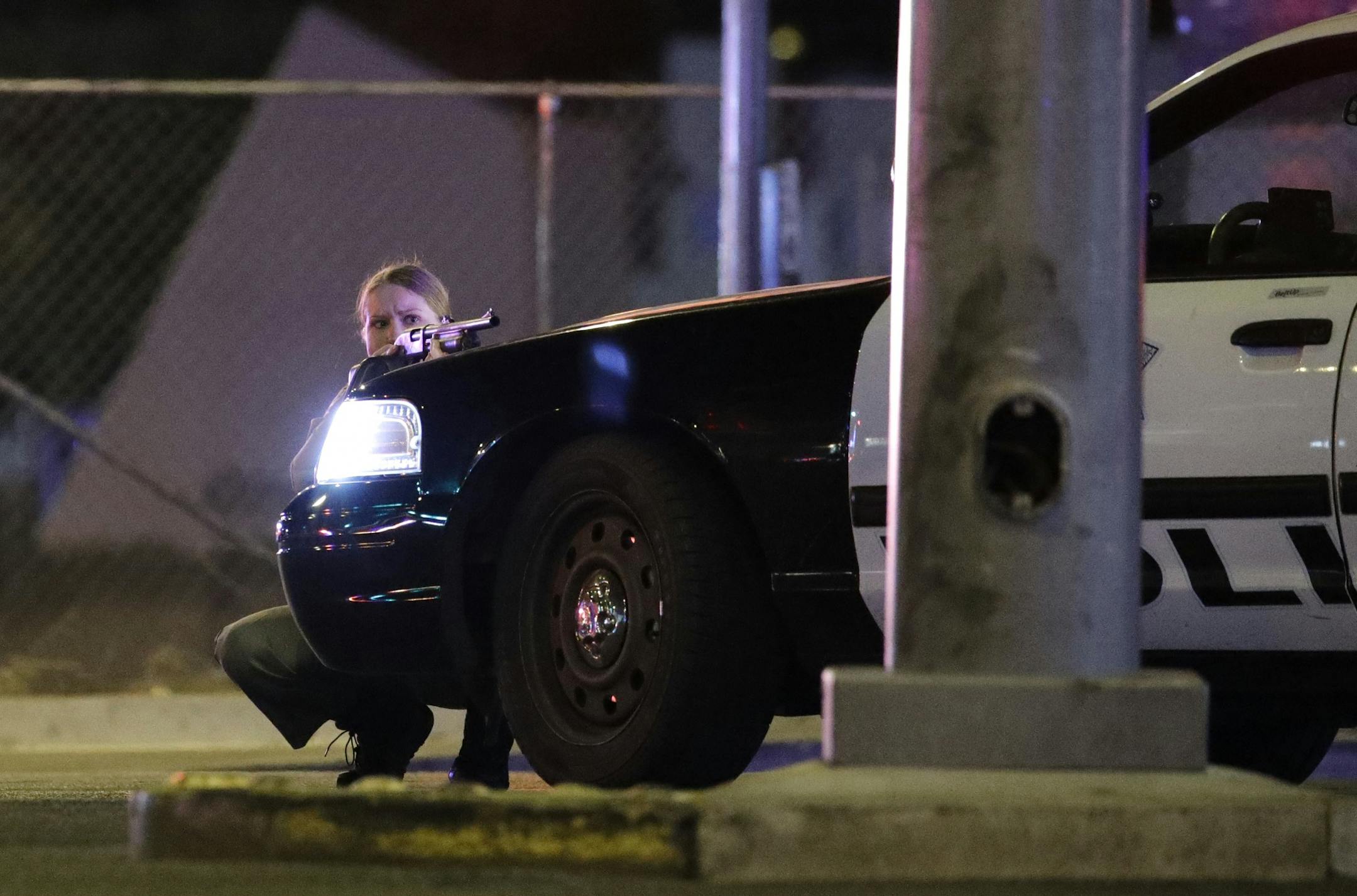 A police officer takes cover behind a police vehicle during a shooting near the Mandalay Bay resort and casino on the Las Vegas Strip, Sunday.