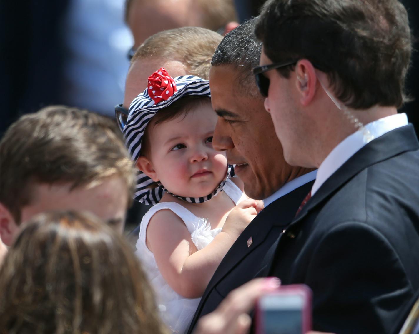 President Obama held a baby as he worked the small crowd after arriving at MSP airport on 6/26/14.]