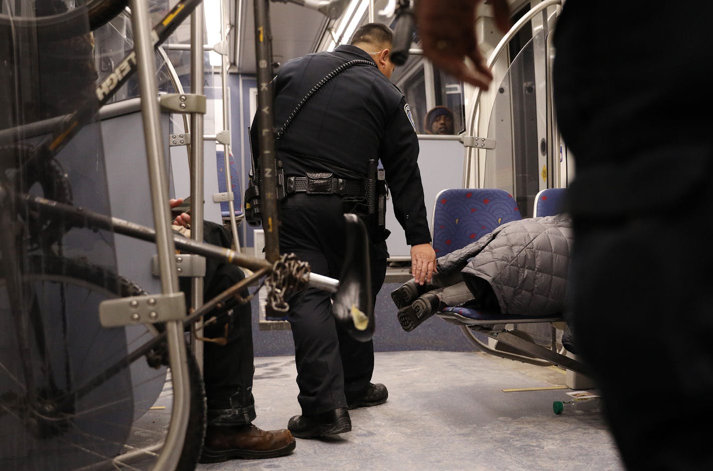 Metro Transit police wake a woman who was sleeping across two seats at night on a light-rail train. ] ANTHONY SOUFFLE &#x2022; anthony.souffle@startribune.com Overnight riders sleep on the Metro Transit light-rail trains Thursday, Dec. 22, 2016 in Minneapolis. Each day, dozens of these sleeping passengers are roused by police, and told to move along. As cold weather finally descends on the Twin Cities, those lacking shelter seek it out in the warm, moving train cars that traverse the downtowns o