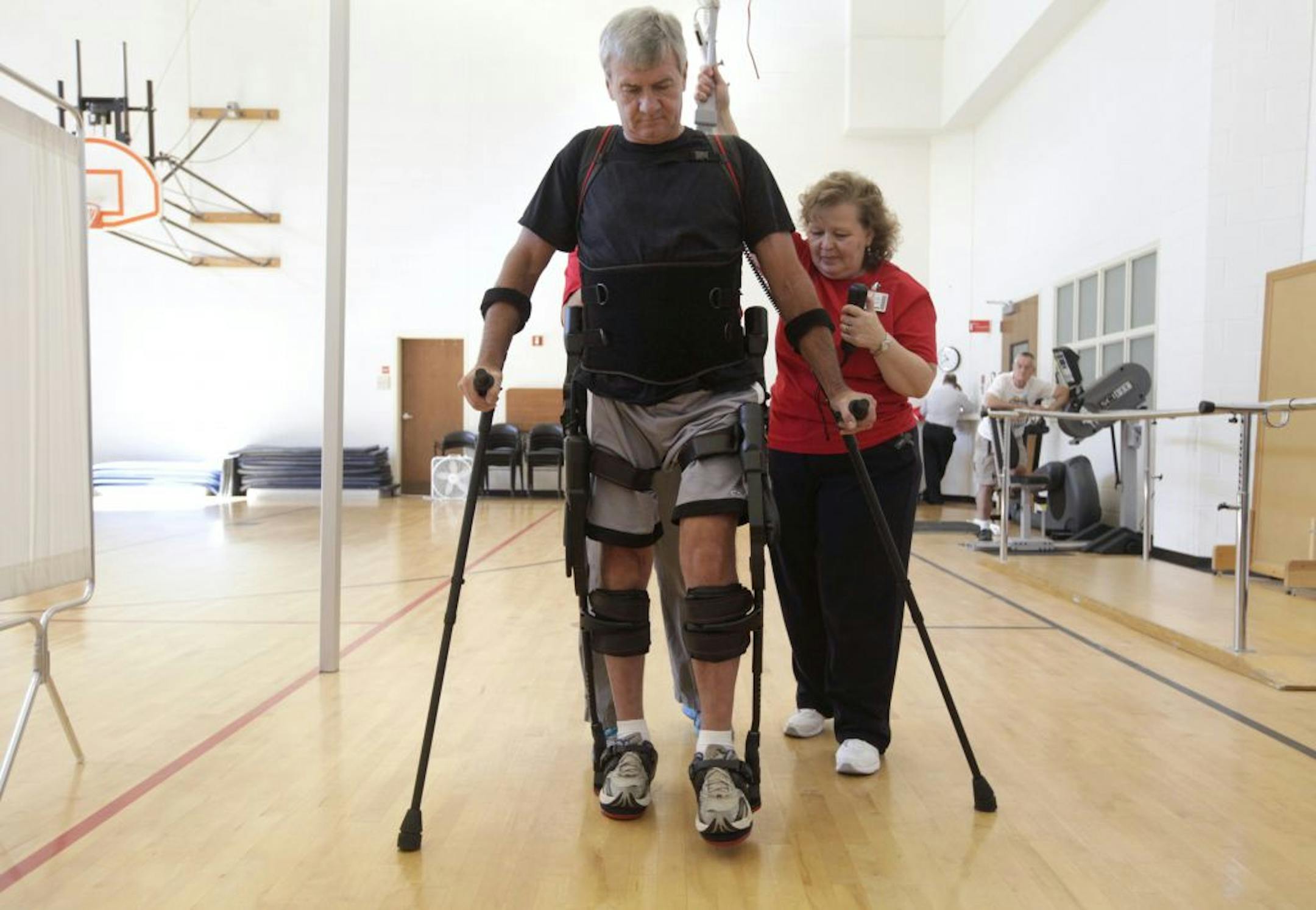 With guidance from physical therapists Nancy Hicks, right, and Nicolle Lang, behind, David Ayscue, 56, wears a robotic exoskeleton to help him walk at WakeMed Rehab in Raleigh, North Carolina, Thursday, September 27, 2012.
