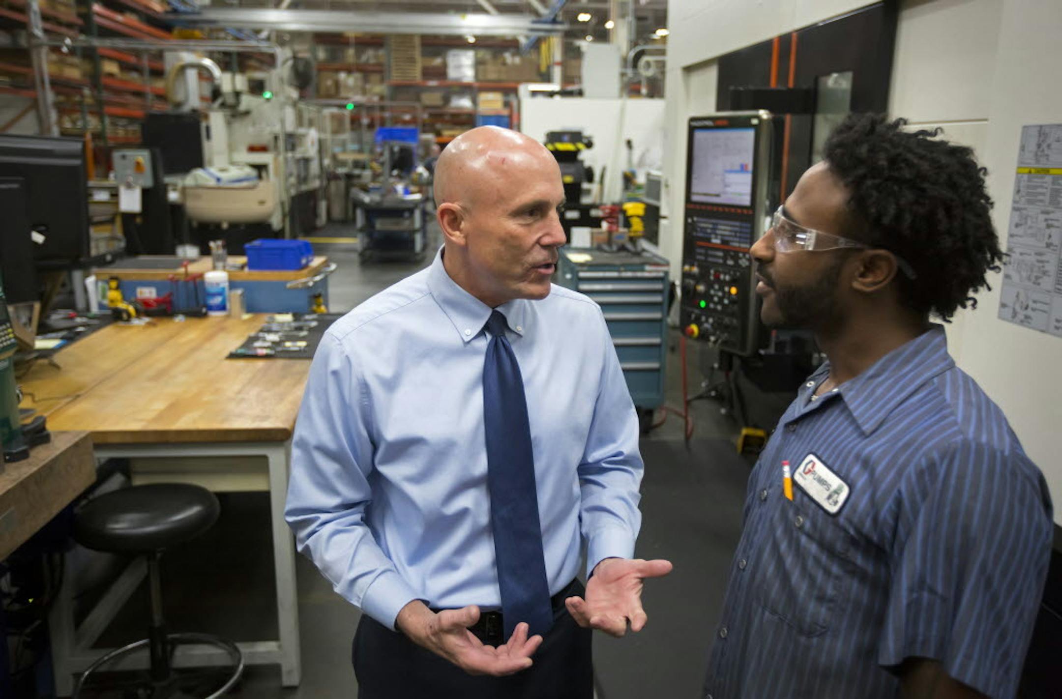 Graco CEO Pat McHale (left) spoke in 2016 with Graco machinist Gadissa Gemeda in the flagship Minneapolis plant.