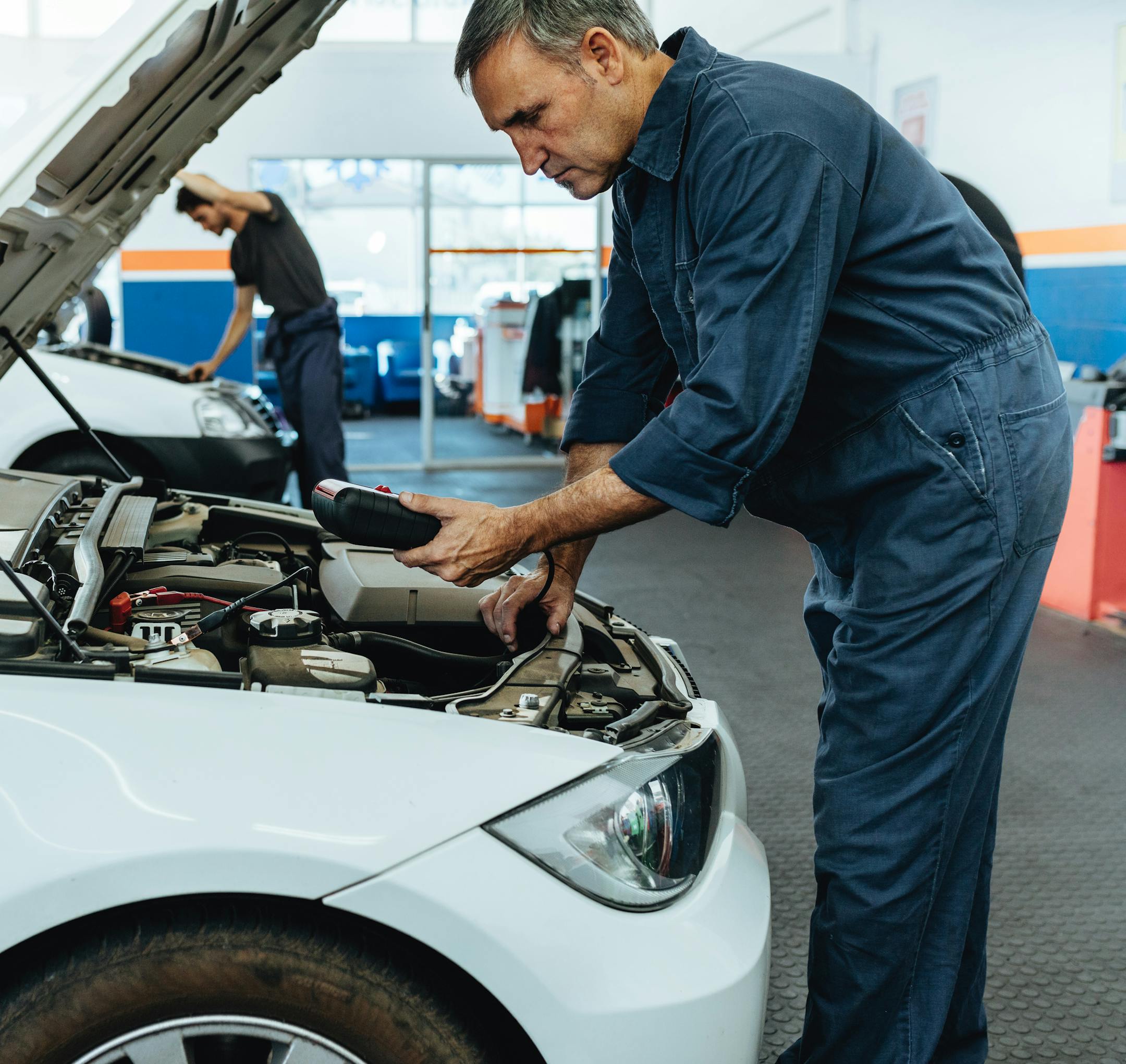 Car mechanic with diagnostic device for reading the error codes. Mechanic checking the car in service station.