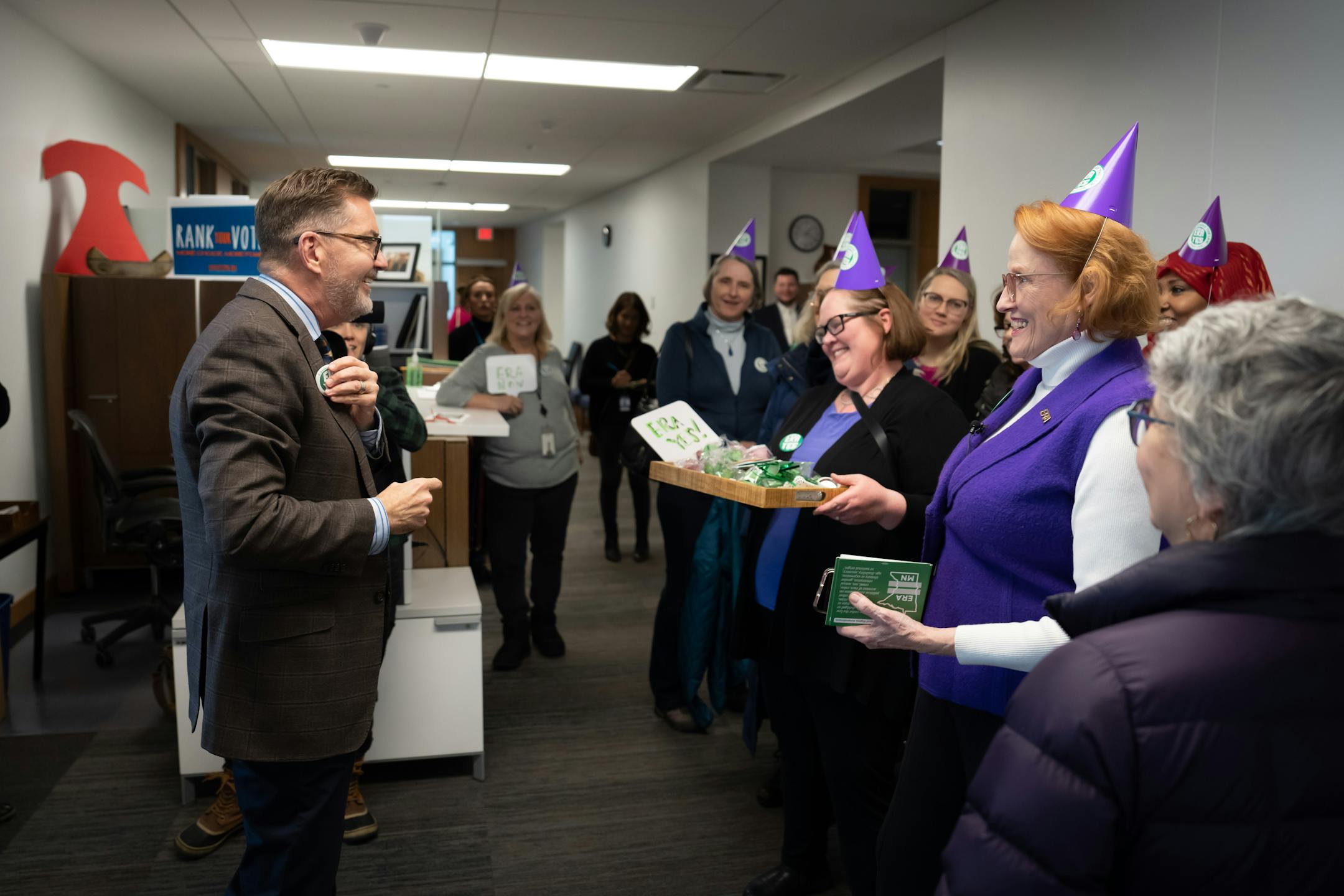 Kate Quinlan-Laird and Betty Folliard, right, smiled as Sen. Scott Dibble, DFL-Minneapolis, left, put an ERA button on his jacket lapel.