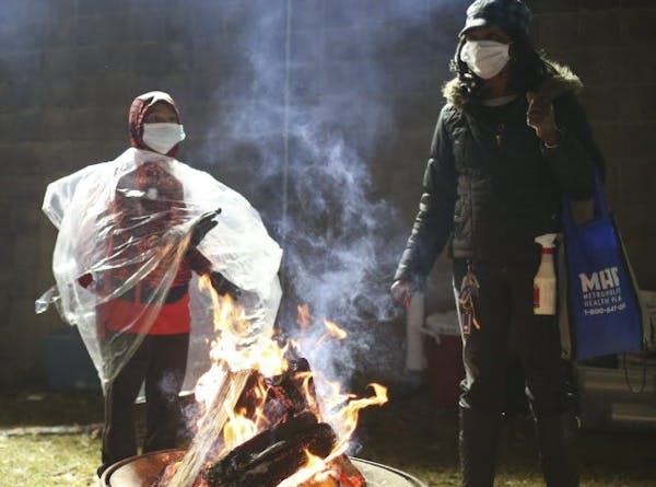 Black Lives Matter protesters warmed themselves around a fire as the protest continued outside the 4th Precinct station Wednesday night in Minneapolis