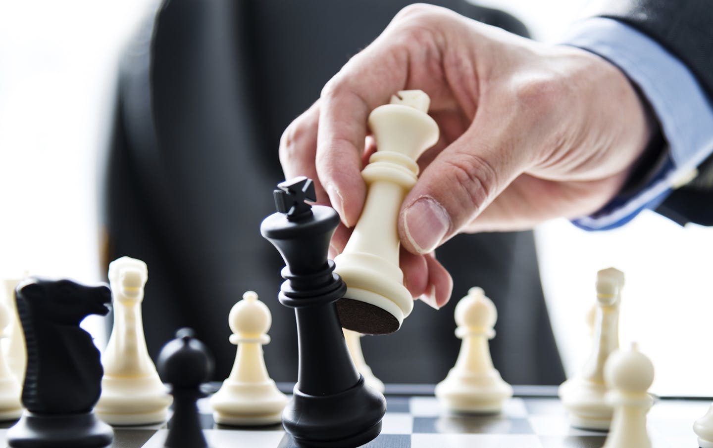 Businessman hand moving the king in a chess game.