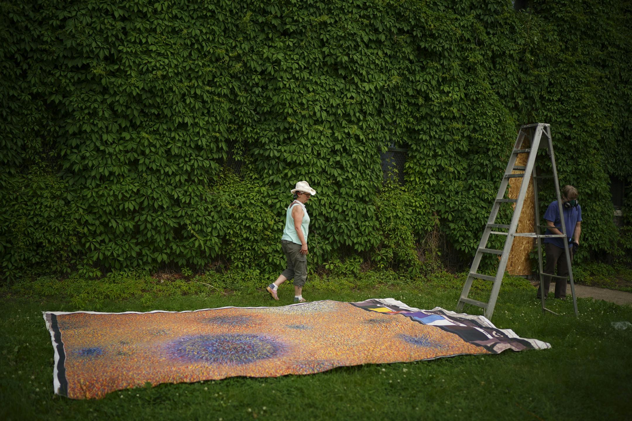 Kathleen Maloney walked past a giant artwork by Aribert Munzner "Genesis, Summer 1965 #9" printed on canvas placed on the lawn outside the Ivy Arts Building to dry.