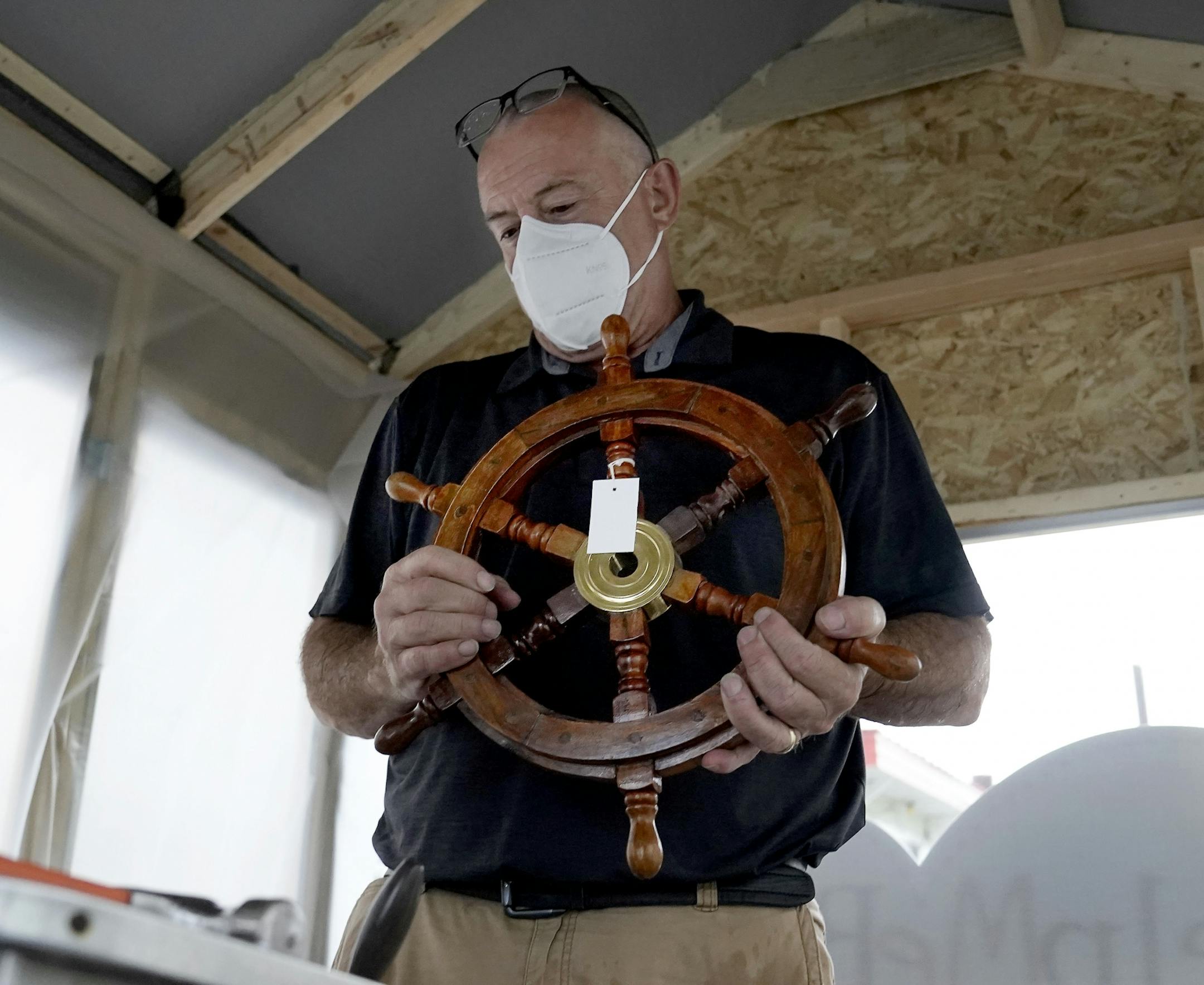 Erich Mische, left executive director of Spare Key, will begin on Aug. 27, a two-month, 1,700 mile journey down the Mississippi River to Baton Rouge, LA, on a raft in order to raise funds for his non-profit and keep it afloat. Here, Mische was seen holding a new boat's wheel that will be installed on the craft Wednesday on Harriet Island where the raft, built upon a small pontoon, is being docked and prepared for the launch in St. Paul.