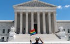 A person waves a rainbow flag in front of the Supreme Court in Washington, on Monday, June 15, 2020. The Supreme Court ruled Monday that a landmark ci