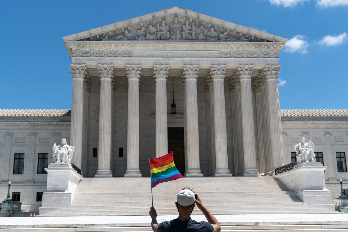 A person waves a rainbow flag in front of the Supreme Court in Washington, on Monday, June 15, 2020. The Supreme Court ruled Monday that a landmark civil rights law protects gay and transgender workers from workplace discrimination, handing the movement for LGBTQ equality a stunning victory. (Anna Moneymaker/The New York Times)