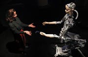 A woman interacts with a robot at the Barbican exhibition centre in London, Wednesday, May 15, 2019. Robots interact with humans at the exhibition 'AI