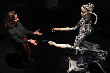 A woman interacts with a robot at the Barbican exhibition centre in London, Wednesday, May 15, 2019. Robots interact with humans at the exhibition 'AI