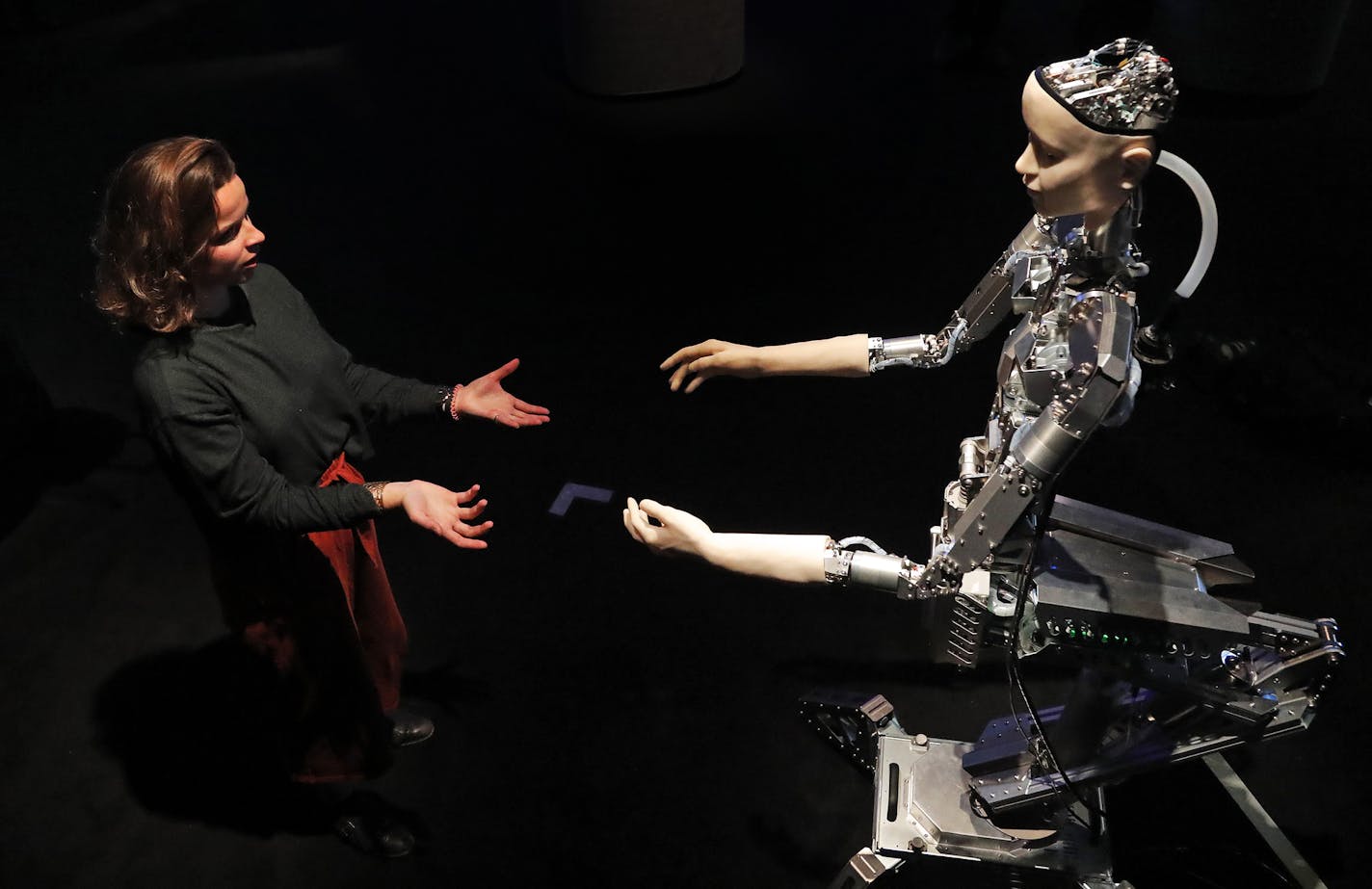 A woman interacts with a robot at the Barbican exhibition centre in London, Wednesday, May 15, 2019. Robots interact with humans at the exhibition 'AI:More than Human' from May 16 until August 26. (AP Photo/Frank Augstein)