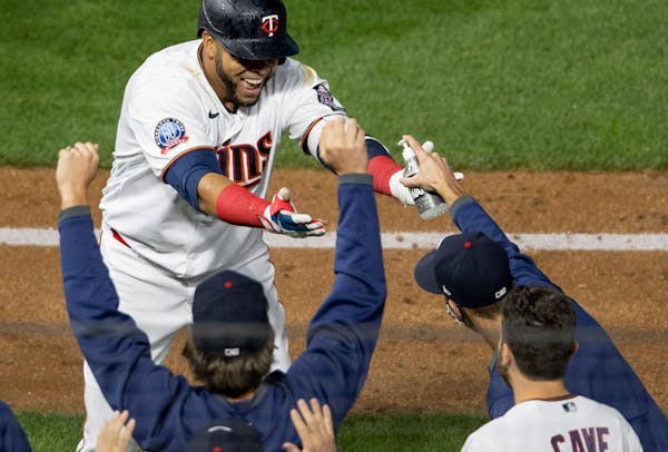 A teammates reached out with hand sanitizer to Minnesota Twins DH Nelson Cruz as he celebrated after the game winning RBI in the bottom of the ninth i
