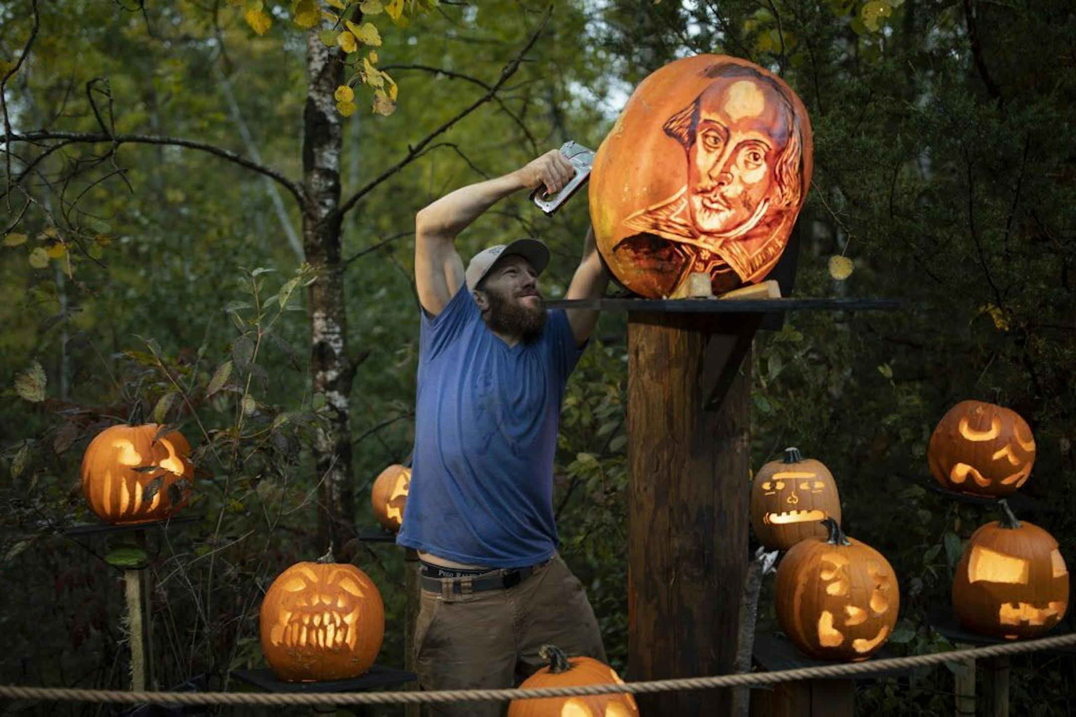 Paul Cadieux stapled a light baffle onto the back of one of the 127 "intricate" carved pumpkins scattered along the trail. It can take as long as eight hours to carve the more elaborate pumpkins.