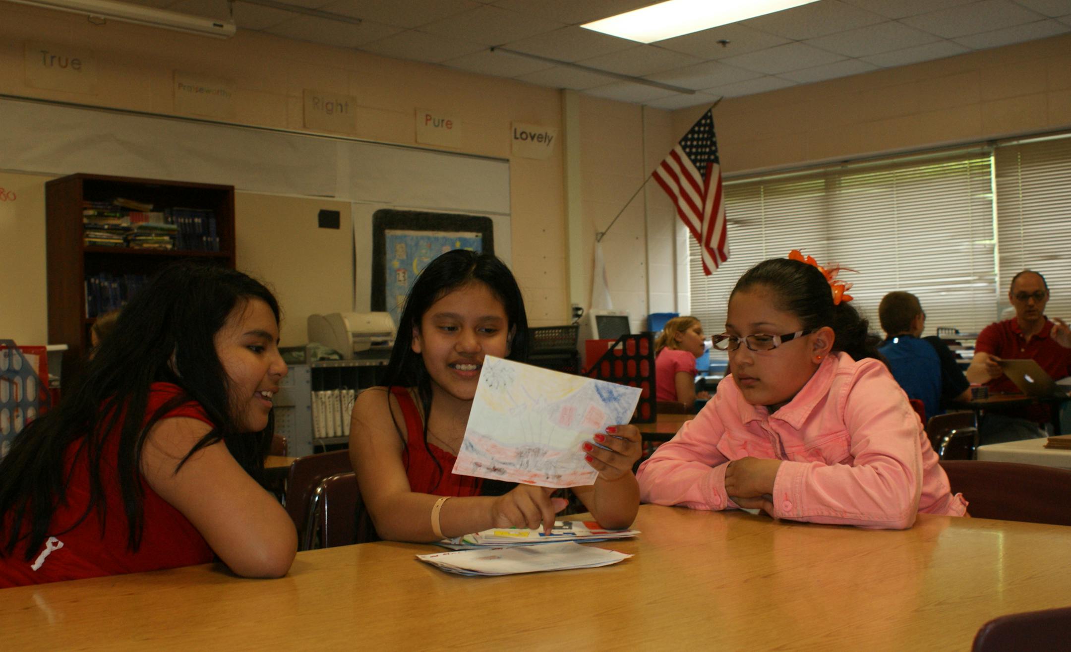 By Erin Adler. Deysi Martinez, Uri Palacios and Karen Martinez look through their "Me on the Map" illustrations.