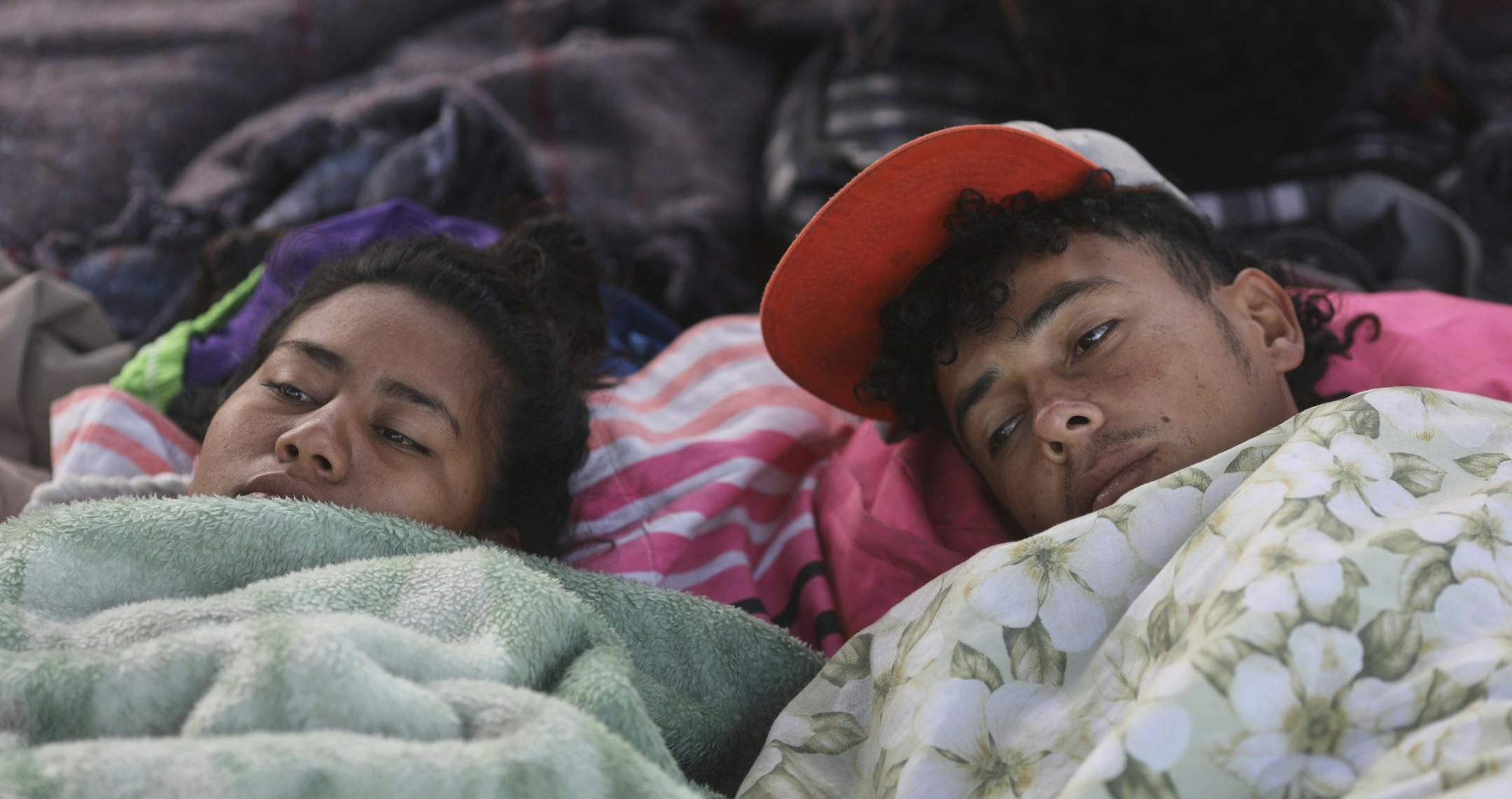 Fabiola Izaguirre and her brother Josue, both of Honduras, begin to wake up after sleeping near the Chaparral border crossing in Tijuana, Mexico, Friday, Nov. 23, 2018. The mayor of Tijuana has declared a humanitarian crisis in his border city and says that he has asked the United Nations for aid to deal with the approximately 5,000 Central American migrants who have arrived in the city. (AP Photo/Rodrigo Abd)