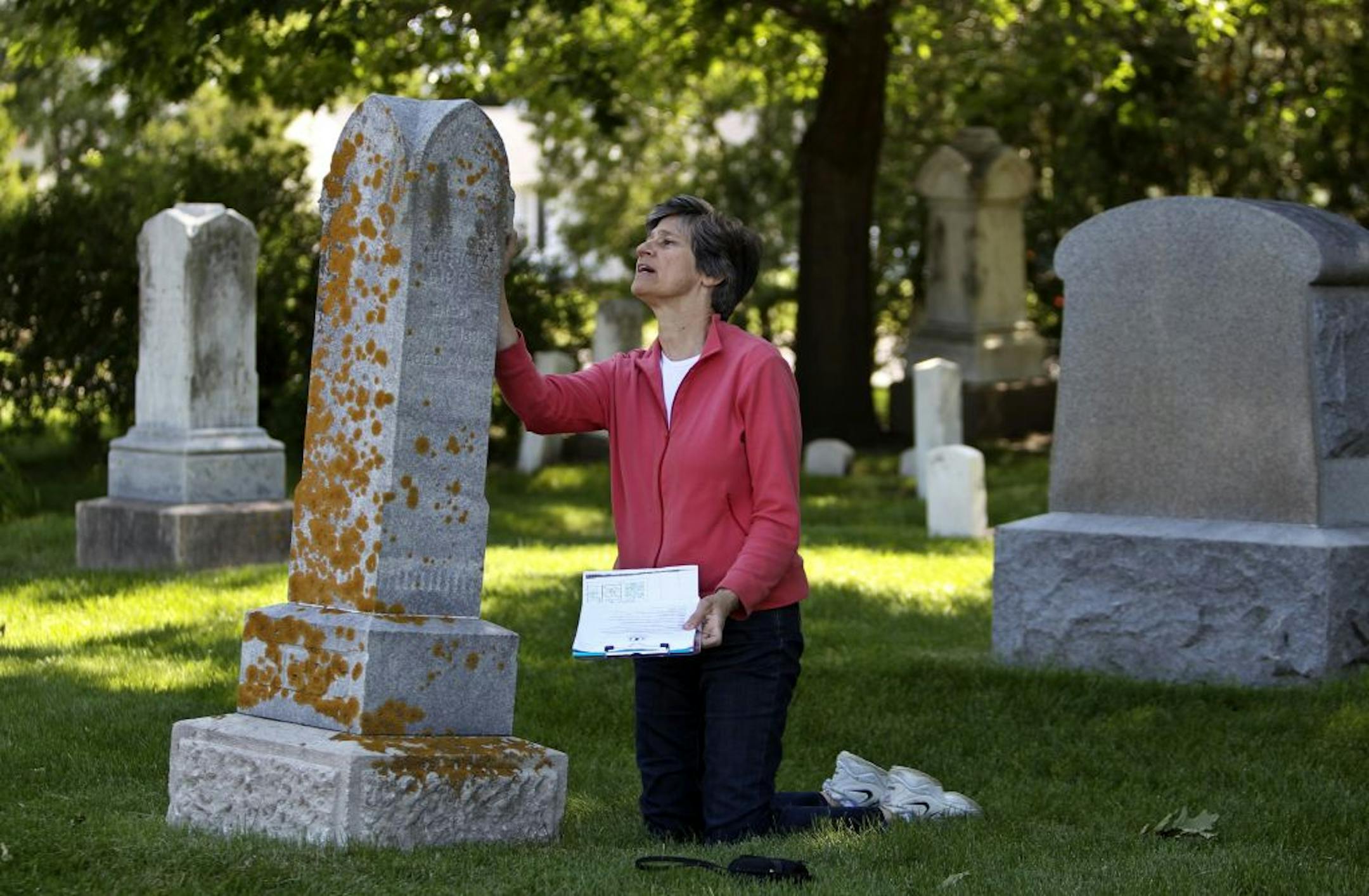 A gravesite marker for the Gibbs family leans heavily to the east as Sue Sorrentino, a board member for the Wayzata Historcial Society, looks over the marker in Wayzata's old cemetery Saturday, June 2, 2012, in Minneapolis, MN.