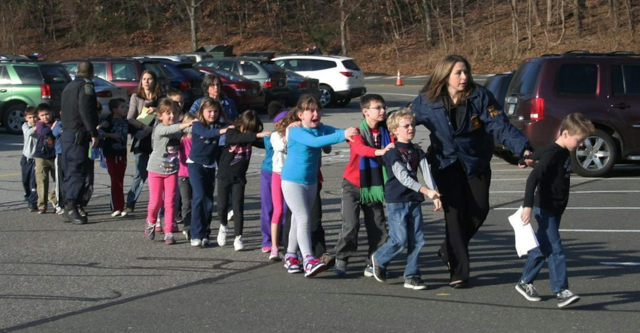 FILE - In this Friday, Dec. 14, 2012 file photo provided by the Newtown Bee, Connecticut State Police lead a line of children from the Sandy Hook Elementary School in Newtown, Conn. after Adam Lanza opened fire, killing 26 people, including 20 children.