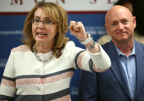 Former Congresswoman Gabrielle Giffords spoke as her husband, Mark Kelly, looked on at the West St. Paul police department in February.