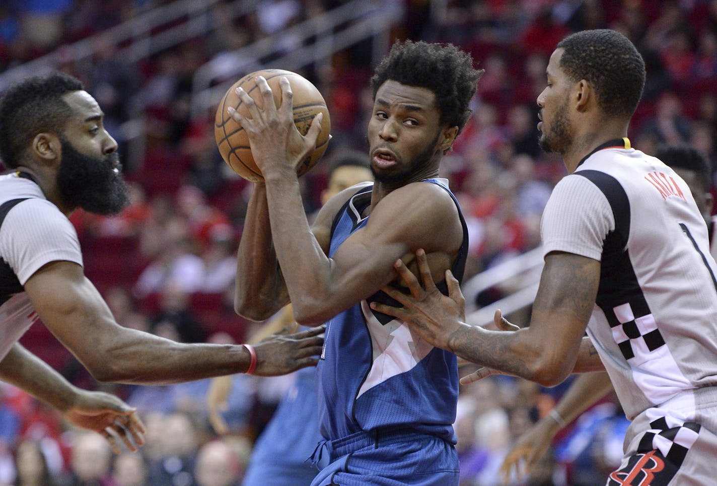 Minnesota Timberwolves forward Andrew Wiggins (22) drives between Houston Rockets guard James Harden, left, and Trevor Ariza in the first half of an NBA basketball game Saturday, Feb. 25, 2017, in Houston. (AP Photo/George Bridges)