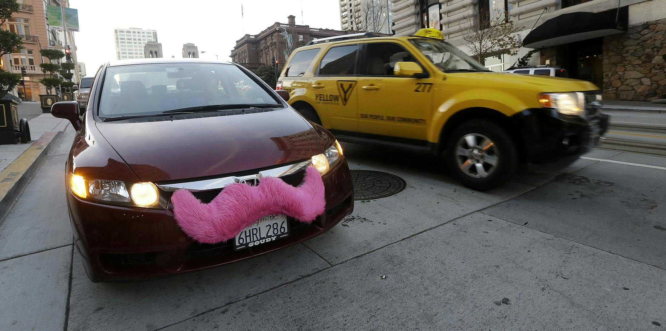 In this Jan. 4, 2013 photo, Lyft driver Nancy Tcheou waits in her car after dropping off a passenger as a taxi cab passes her in San Francisco. Fed up with traditional taxis, city dwellers are tapping their smartphones to hitch rides from strangers using mobile apps that allow riders and drivers to find each other. Internet-enabled ridesharing services such as Lyft, Uber and Sidecar are expanding rapidly in San Francisco, New York and other U.S. cities, billing themselves as a high-tech, low-cos