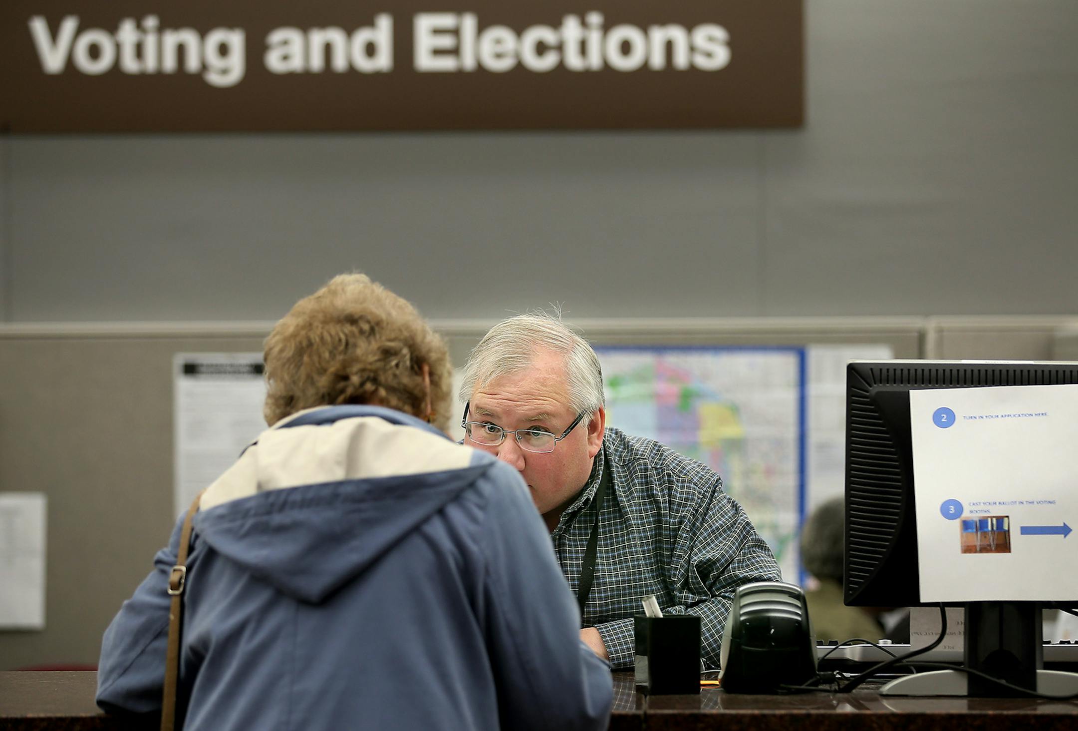 Hennepin County Voting and Elections Office Specialist Andrew Krueger helped voter Mary Ellen Gallick with her ballot at the absentee-voting polls at the Hennepin County Government Center, Thursday, October 23, 2014 in Minneapolis, MN. ] (ELIZABETH FLORES/STAR TRIBUNE) ELIZABETH FLORES &#x2022; eflores@startribune.com