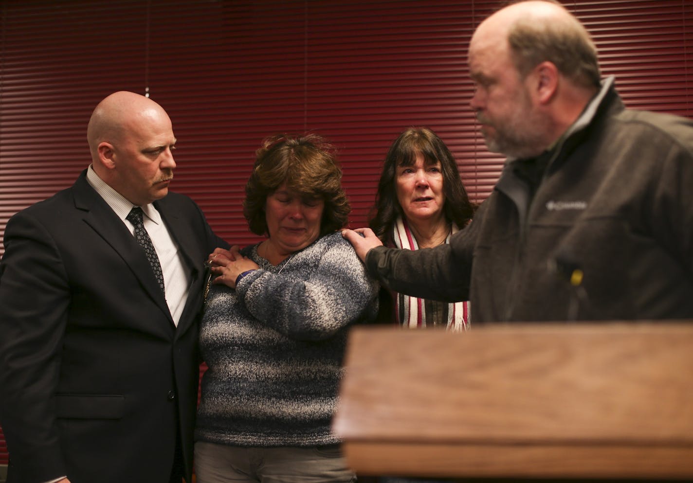 Scott Patrick's brother, Mike Brue, reached back to Patrick's widow, Michelle, after he spoke to reporters on behalf of the family after the guilty verdicts in the Brian Fitch trial were announced Monday night in the Stearns County Sheriff's Office in St. Cloud. At left is Mendota Heights police officer Tanner Spicer.